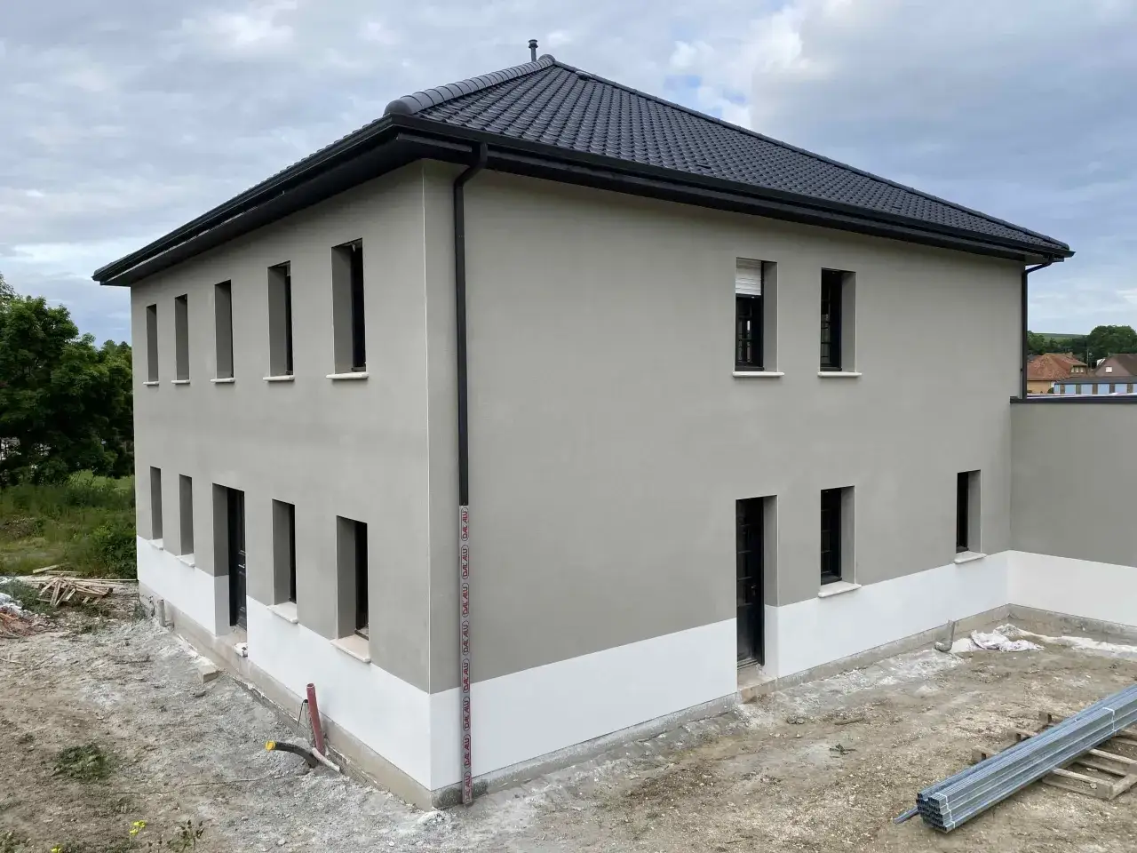 Maison moderne avec fa&ccedil;ade grise et blanche, pr&ecirc;te &agrave; refaire sa fa&ccedil;ade soi-m&ecirc;me. Le chantier est en cours.