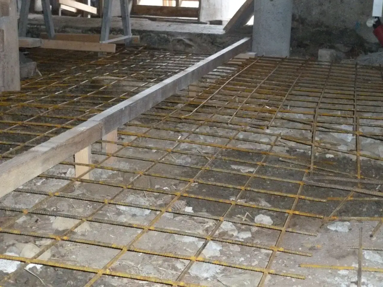 Grillage m&eacute;tallique pos&eacute; sur le sol, pr&ecirc;t pour le coulage du b&eacute;ton. L'&eacute;paisseur dalle b&eacute;ton garage sera d&eacute;termin&eacute;e par la suite.