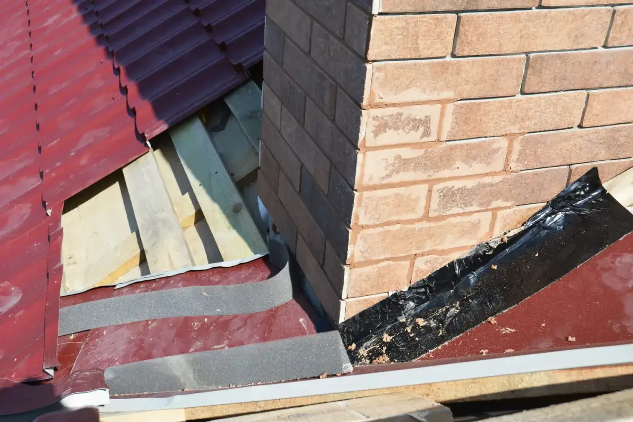 Travaux d'étanchéité cheminée en cours sur un toit en tuiles rouges. Isolation et protection contre les intempéries.