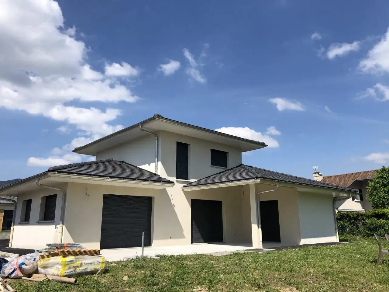 Maison moderne en construction, façade crème, volets gris. Idéal pour estimer le prix peinture m2.