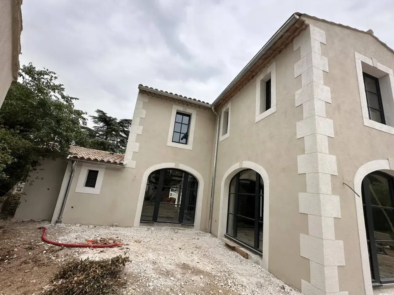 Maison en cours de r&eacute;novation. On refait un enduit ext&eacute;rieur sur un enduit existant, avec des encadrements de fen&ecirc;tres en pierre.